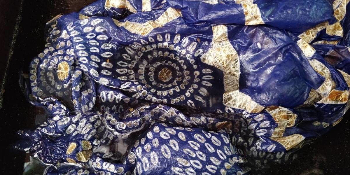 A blue silk scarf in abstract floral pattern showing the Indonesian batik printing with wax still present on the fabric.