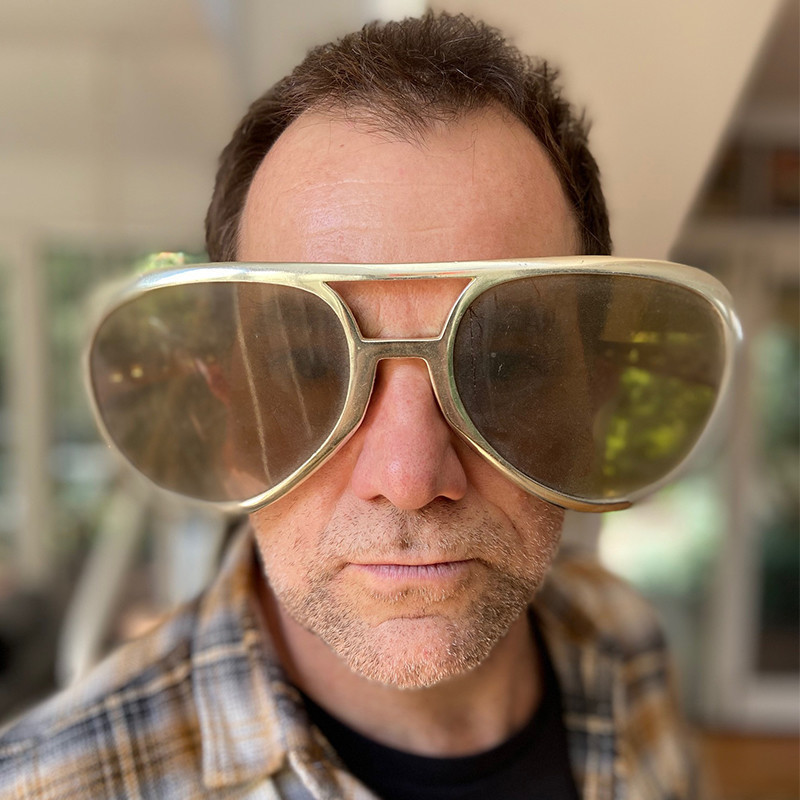 Lehmo: 2020 Vision - A headshot of a man with short brown hair and grey stubble wears comically large oversized sunglasses.