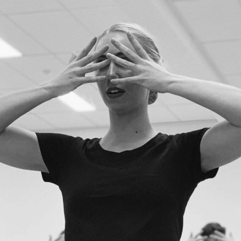 CANCELLED – Metronome - A black and white photograph of a woman wearing a black t-shirt. She is covering her face with her hands and her hair is tied back.
