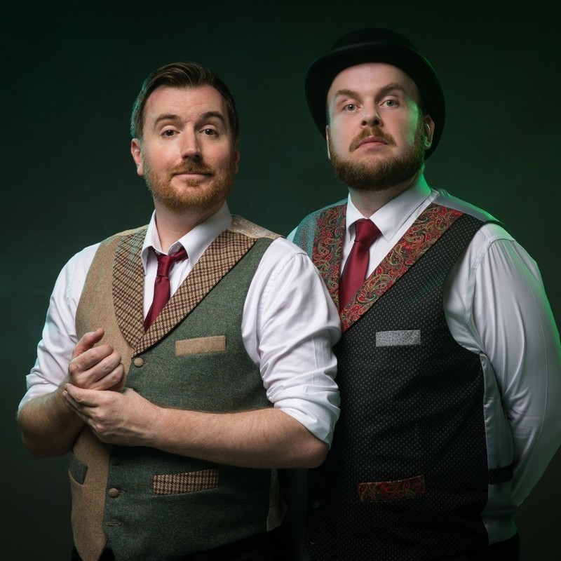Innes Lloyd: Journey to the Centre of the Earth - Two rather dapper men dress resplendently in intricately designed waistcoats stand together with a confident, dignified posture ready for comedy and adventure.