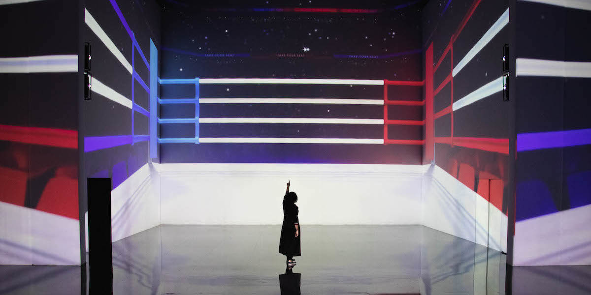 Performer pointing up to a projection of a boxing ring