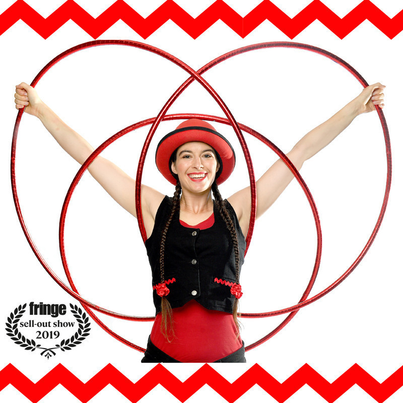 Luth, a woman dressed in red & black costume, smiles while holding up hula hoops in a butterfly shape