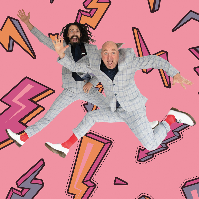 Two men jumping up in the air wearing identical checkered suits. They are looking directly at the camera with looks of surprise in their faces.