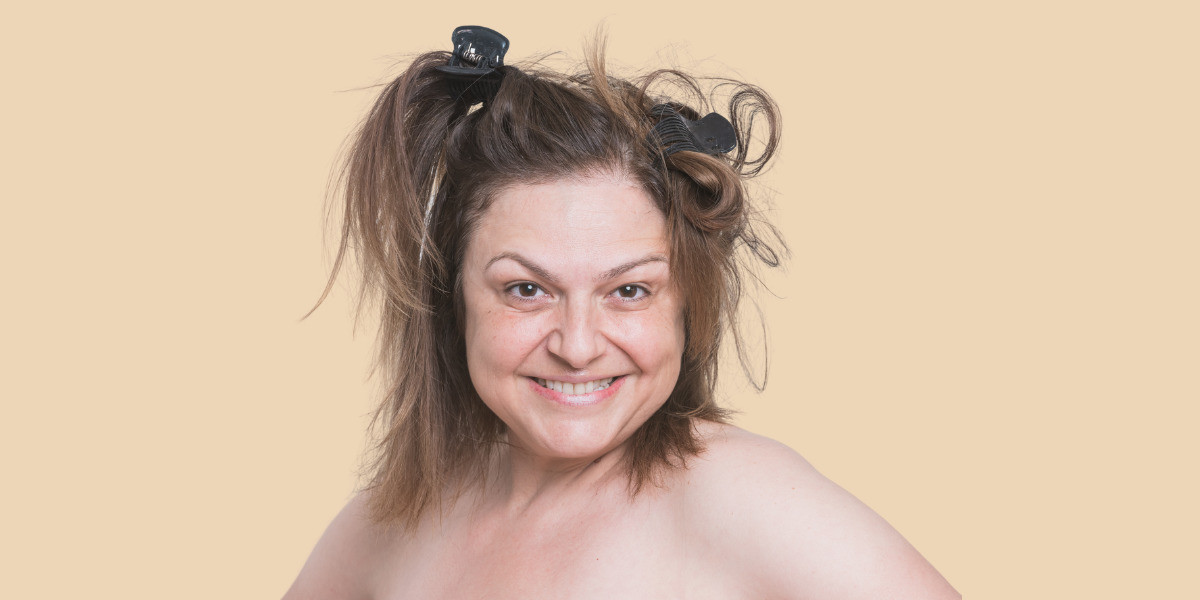 A crazed naked woman is smiling at the camera with her hair up.