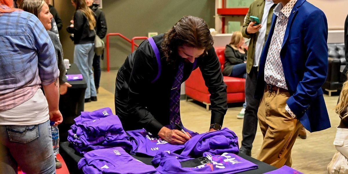A picture of Alex Mackenzie signing t-shirts after a show
