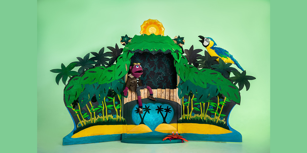 Pico the main character sits relaxing on a tropical island. There is a parrot in the trees and a red crab on the sand.