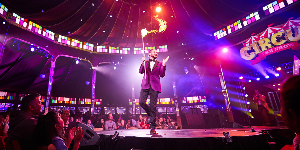 Live performance of magician on stage holding a pole with the top on fire.