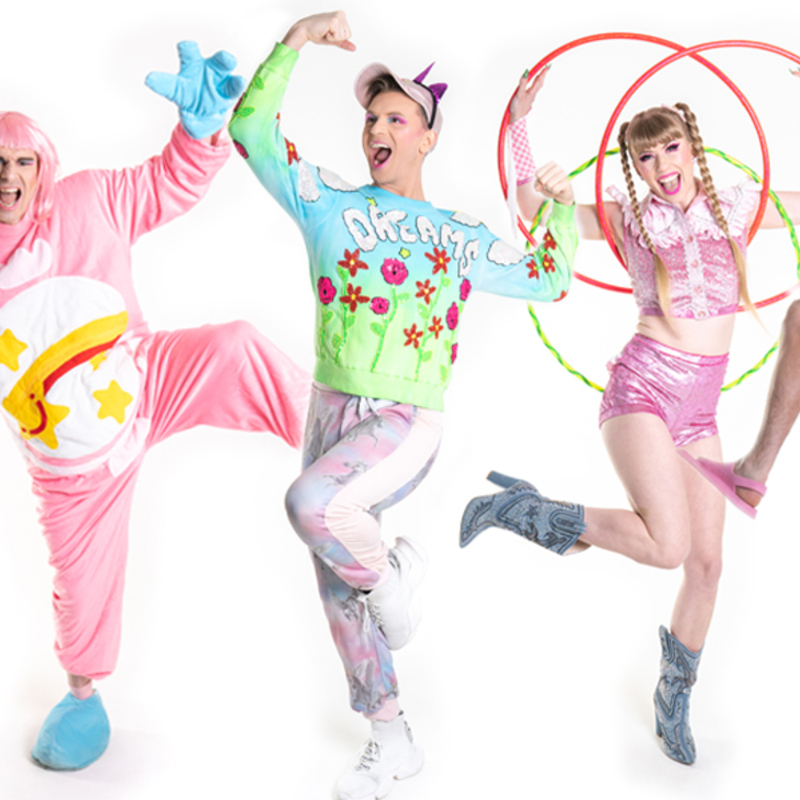 Five performers in colourful and bright costumes pose in a row.