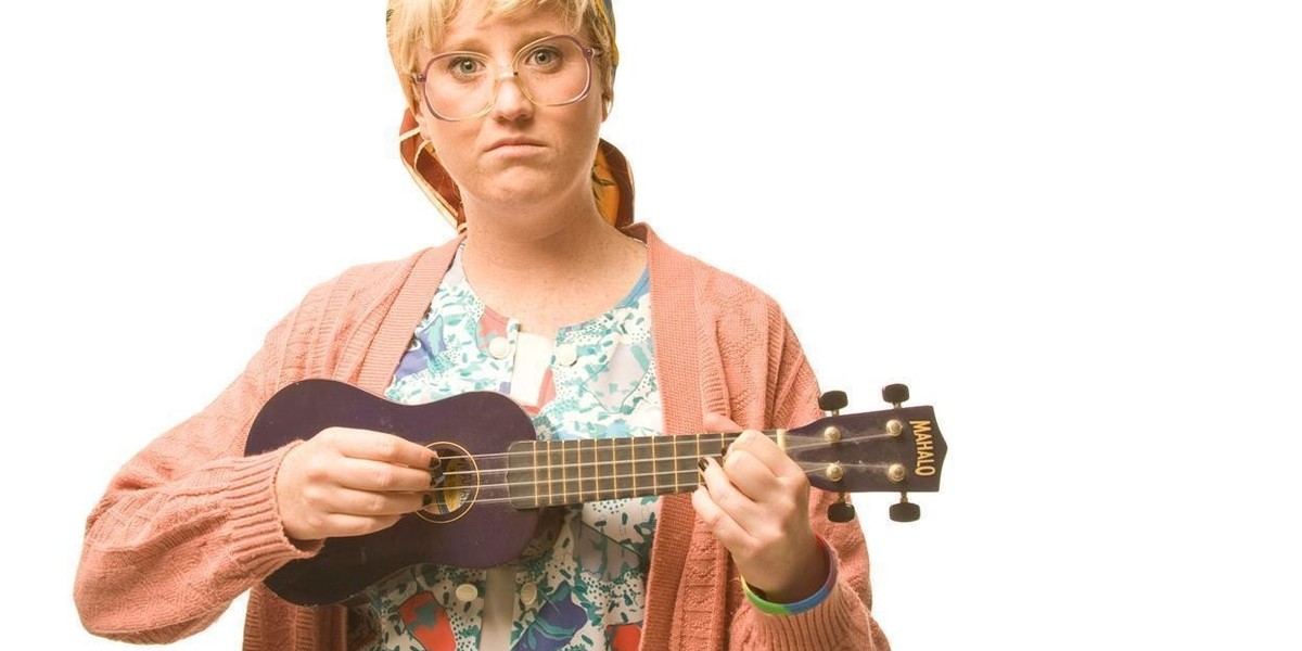 Granny flaps holding her ukulele looking serious at the camera