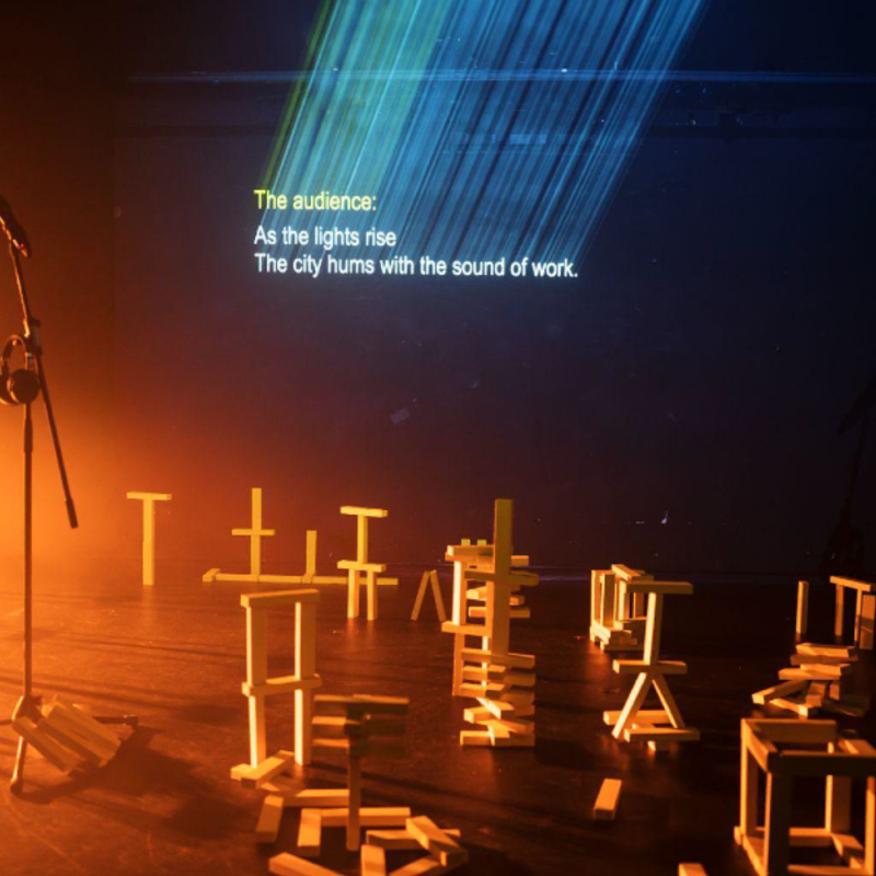 A microphone on a dark stage surrounded by yellow jenga blocks
