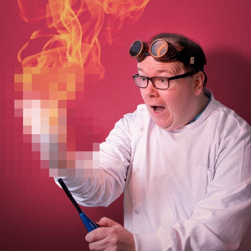 Science Magic XXX - Man in labcoat and goggles, looking shocked as his hand is on fire. However the hand and fire are pixelated, as if hiding something obscene.