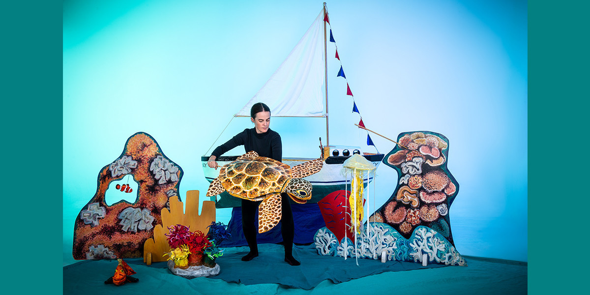 The puppeteer holds a sea turtle.