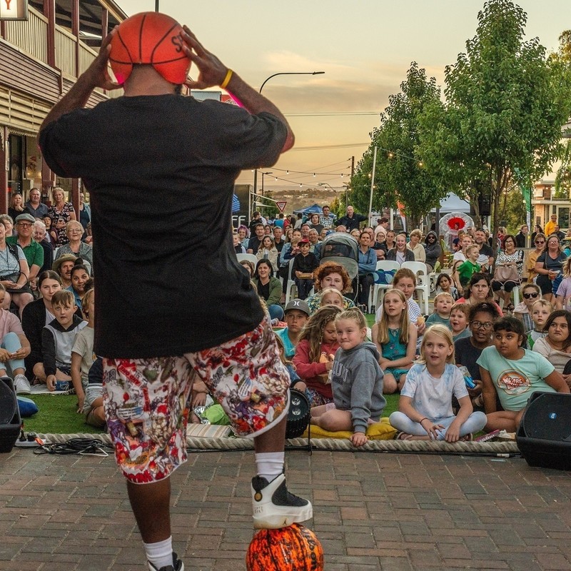Basketball man performing in Sixth Street, Murray Bridge with a large audience mainly of children