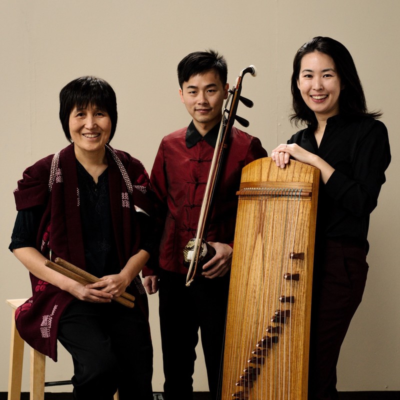 San Ureshi members, Satomi Ohnishi holding a pair of oriental drum stick, David Dai with Chinese Violin called Erhu, and Zhao Liang standing with Chinese harp - Guzheng.