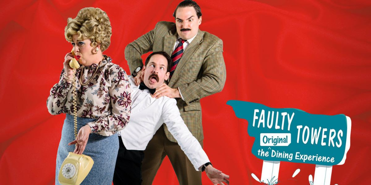 Three actors stand in front of a sign from Fawlty Towers. The female is on the phone while behind her a taller man is choking a shorter man.