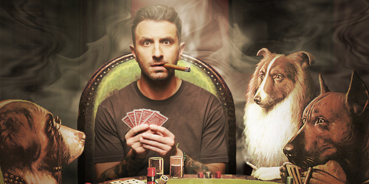 Tommy sits at a poker table, surrounded by dogs. He holds cards in his hands and smokes a cigar.