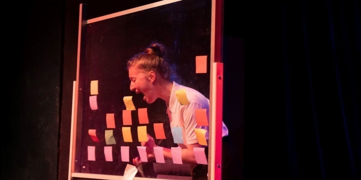 A teenage girl screaming a clear whiteboard full of post it notes.