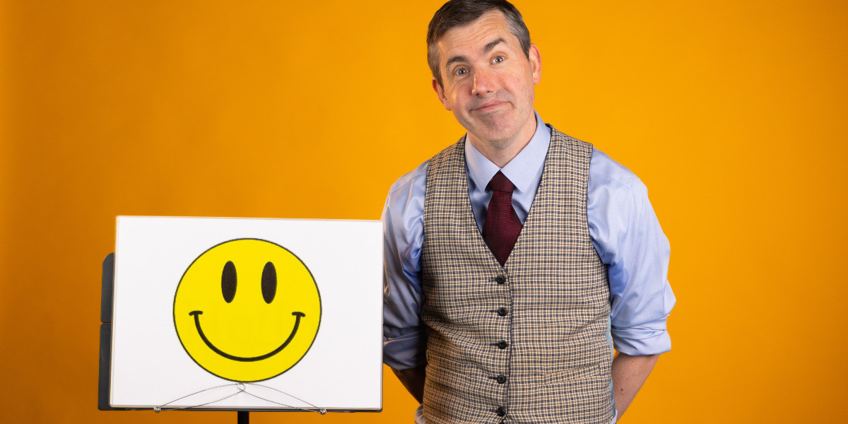 Person in waistcoat standing next to an image of a smiling face.