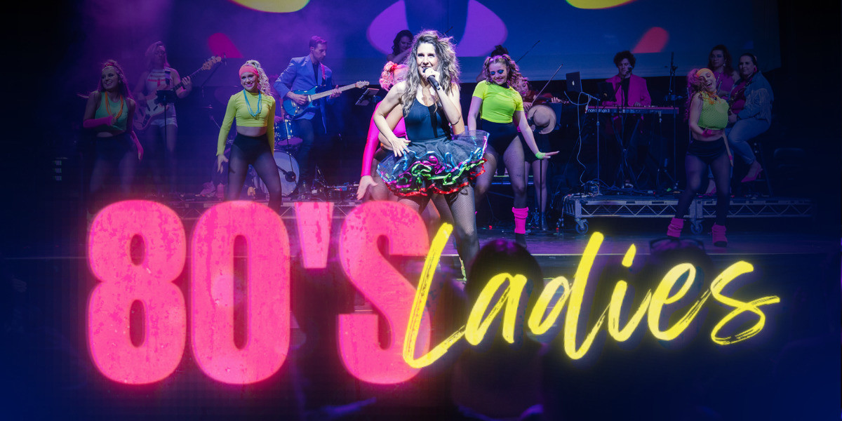 4 women dressed in fluorescent 80's style clothing are dancing and singing. Band dressed in colourful clothing playing instruments in the background. "80's Ladies" as text in the foreground.