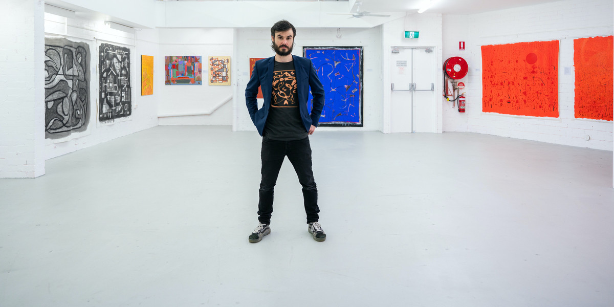 Sam Kissajukian: Paintings of Modernia - Sam stands in front of his paintings