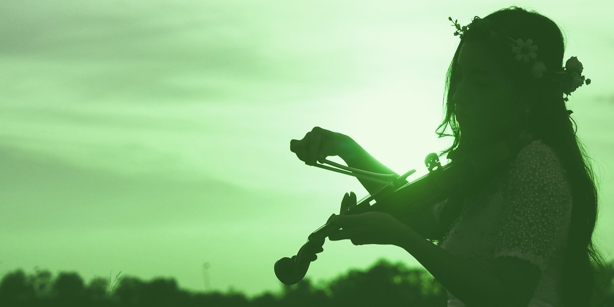 A hazy image of a girl with flowers in her hair playing the violin outside, against a backdrop of the sky.