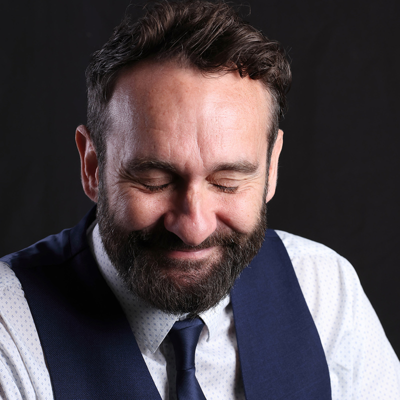 headshot, shirt, tie, waistcoat. Eyes closed possibly laughing after just hearing a joke