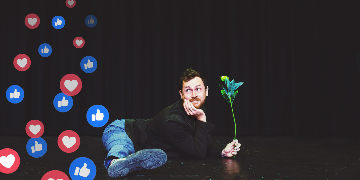 The background is black and a man is in full splits sideways. He is wearing blue jeans and a dark skivvy. he has a red rose in his hands and is smiling. There is a number of like symbols behind him which looks like he's farting likes!