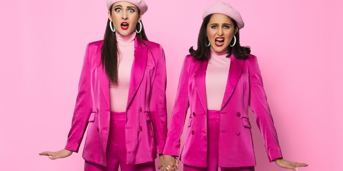 Two girls in pink suits. They both were match berets. They are striking a sassy pose.