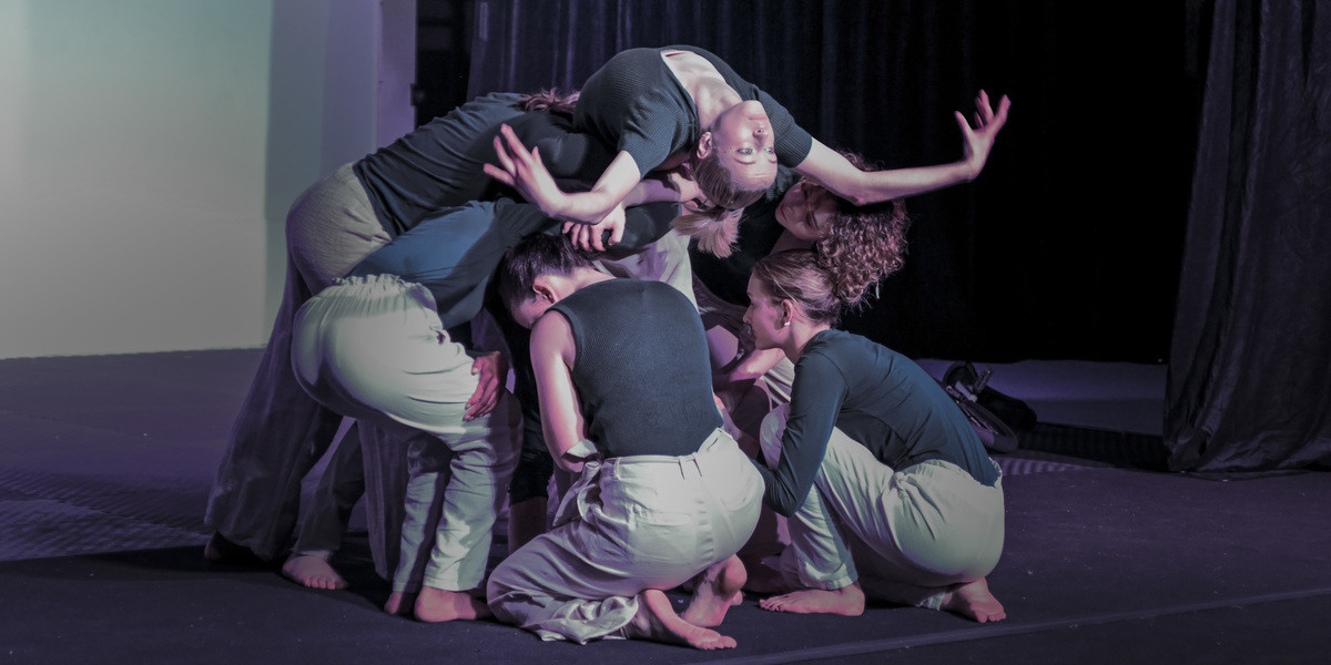 Group of teenagers holding each other up with 1 looking upside down in a back bend