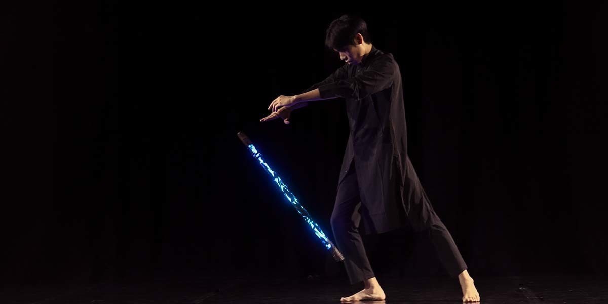 An Asian man playing with a streak of blue light.
