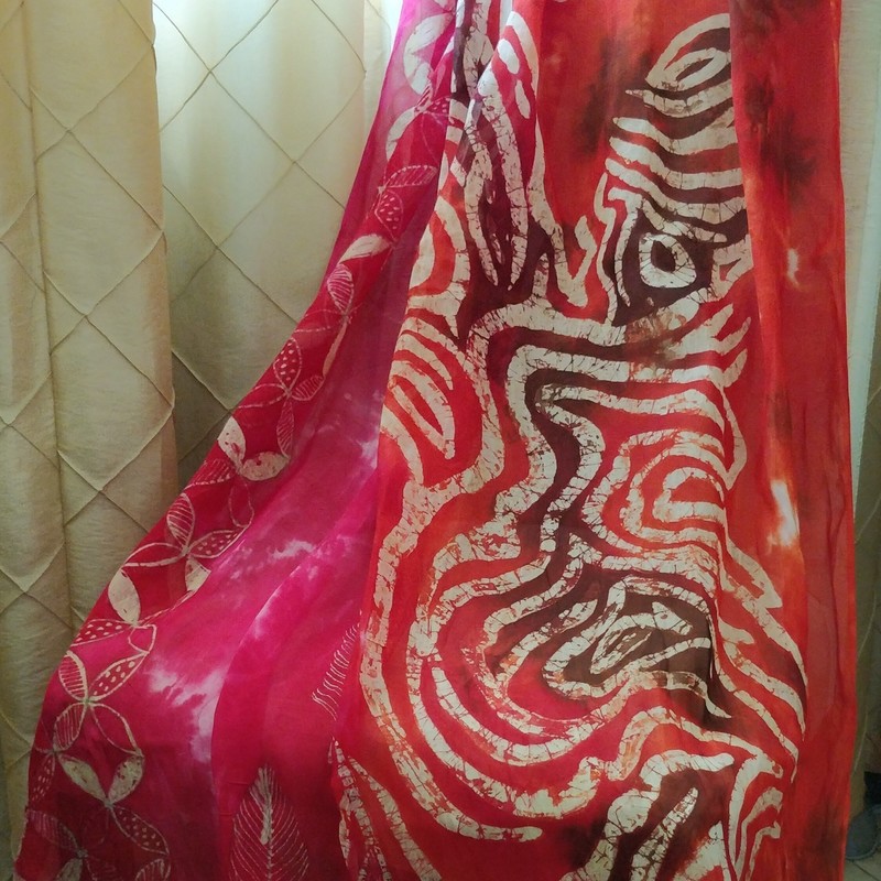 A draped red, pink, brown and white batik patterned silk scarf.