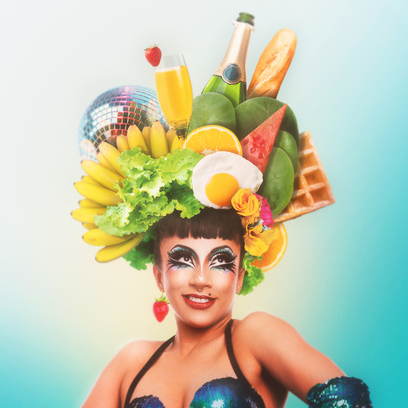 Jazida wears a collage of brunch themed items as a headdress including a hand of bananas, a mimosa glass, a waffle, fried egg, champagne bottle and a disco ball.