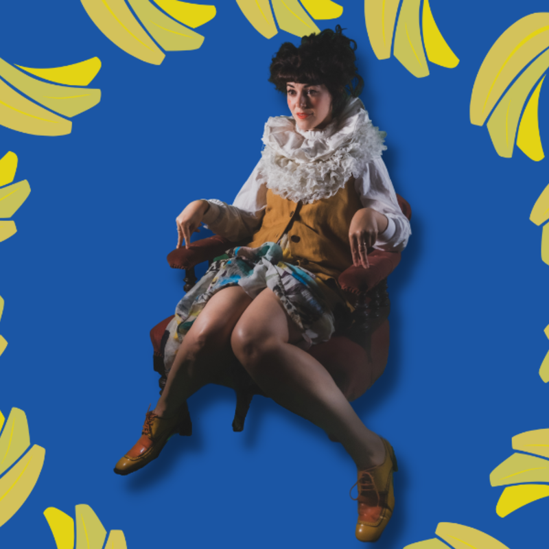 Britt slouches in a chair. There is a blue background and surrounded by bananas.