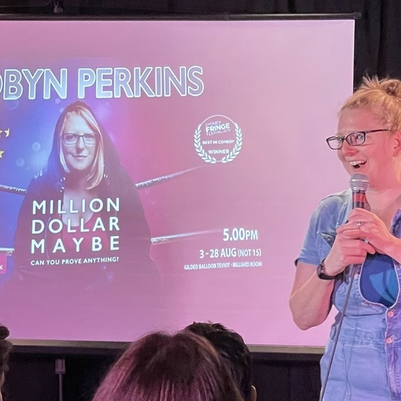 A photo of Robyn Perkins, performing the show in front of a projector.