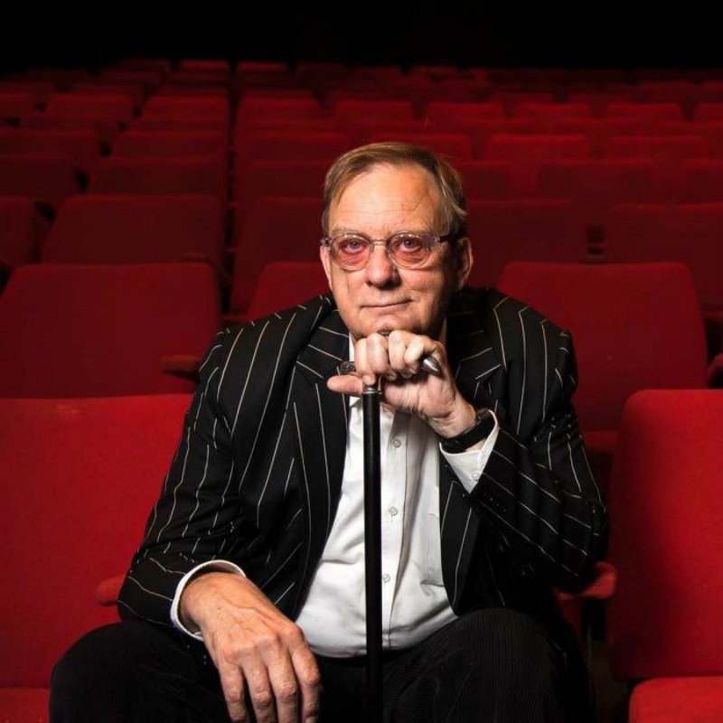 PETER GOERS is FIT, FABULOUS AND NEARLY FIFTY!!! - Peter Goers sitting with a cane in a theatre with the red theatre seats behind him.