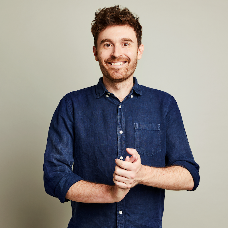 Image of man looking forward and smiling with hands clapped together