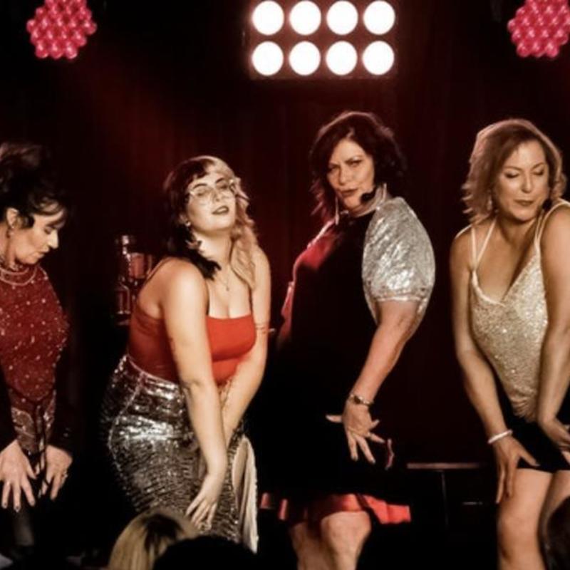 Five of the housewives pose suggestively on stage while another sings.