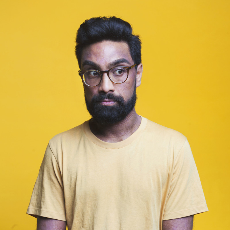 A handsome photo of Suren, looking slightly off camera. He's wearing a yellow t-shirt while stood in front of a yellow background. This is testimony to both his fashion sense and ability to plan.