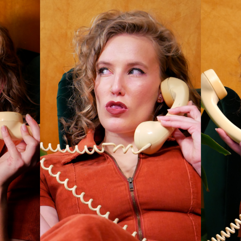Three images, side-by-side, of a white woman with curly, dark blonde hair. She is wearing a burnt-orange, collared, corduroy jumpsuit, sitting in a dark-green armchair against a mustard-coloured backdrop and next to a leafy green plant. She holds a corded rotary phone. In the first image she is laughing with her eyes closed, tongue sticking out of her mouth. In the second she is sucking her teeth and looking to the left suspiciously. In the third image she is smiling joyously with her mouth open.