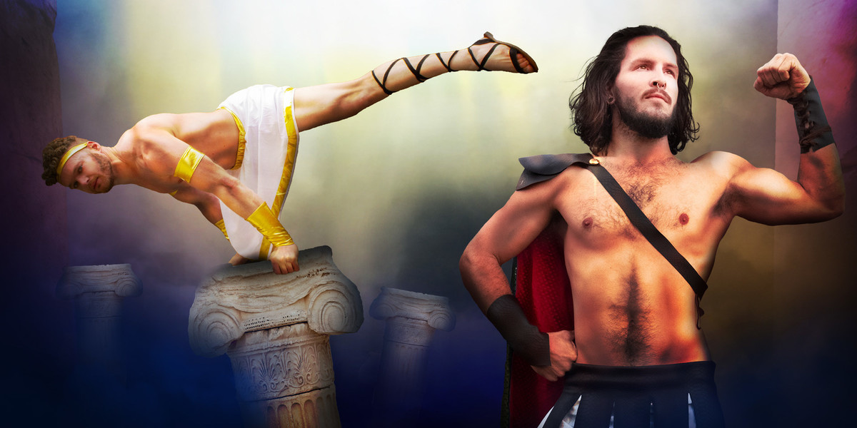 Two acrobats dresssed as greek gods side by side, one is in the foreground in a hercules outfit, performing a classic pose of flexing one arm and one arm on the hip, the other is in all white and gold, and is performing an acrobatic trick.