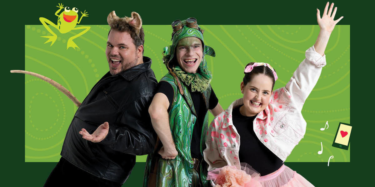 A trio of young performers with wide jovial smiles at camera: a young man is dressed as a rat wearing a leather jacket, rat ears and tail, another young man dressed as a frog inspired by punk steam fashion, and a young woman dressed in frilly pink skirt and pink denim jacket.