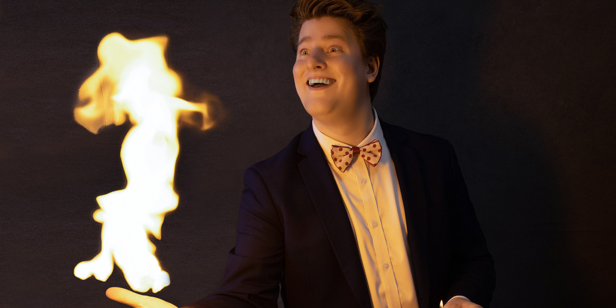 A man in a blue suit with flames coming out of his hand