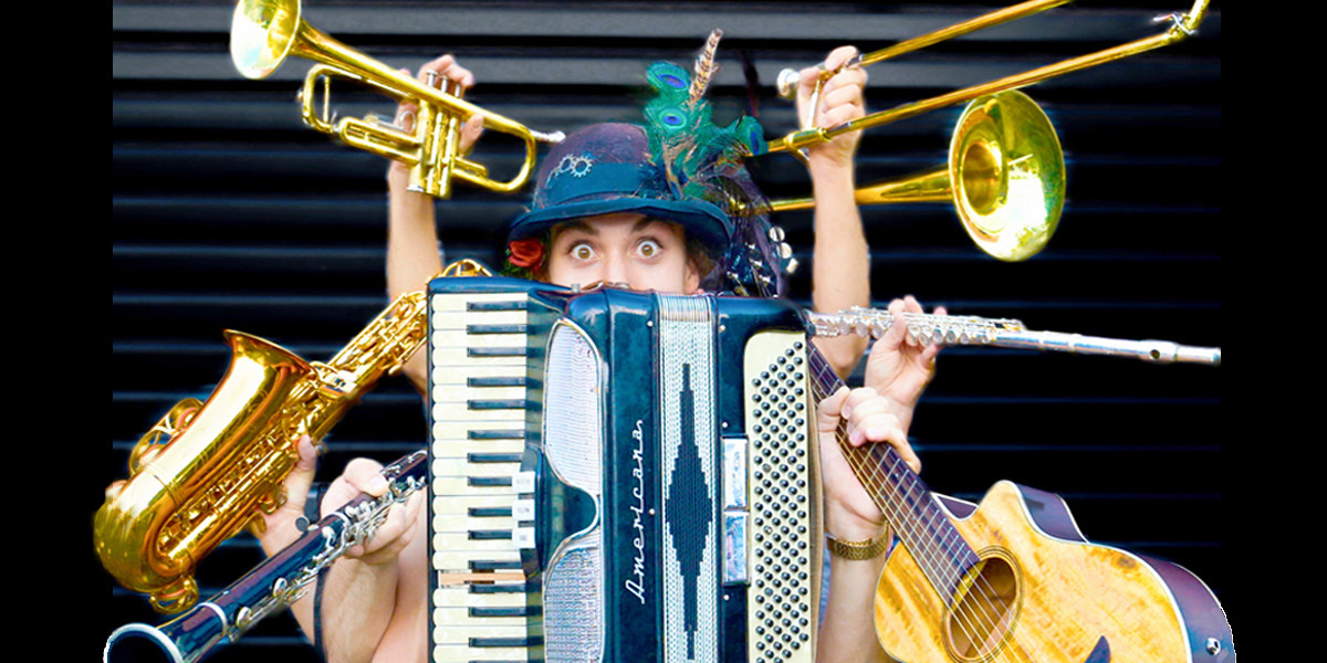 Multi-instrumentalist Jai Lee, musician for Funky Fresh Improv, surrounded by a trumpet, accordion, saxophone, guitar, clarinet, trombone and a flute.