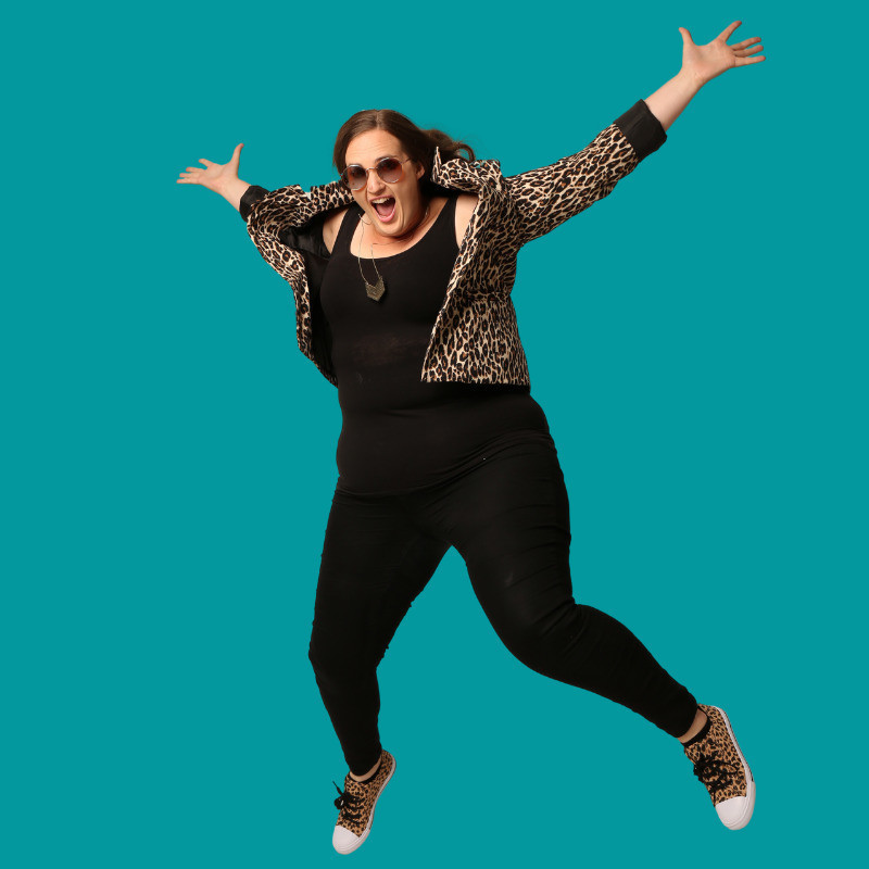 The comedian Eddy Rockefeller is pictured mid-air with arms outstretched, mouth wide open, and clothed in cougar print apparel.
