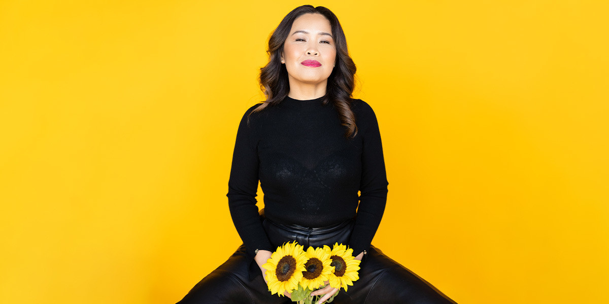 Diana Nguyen: Sunny Side Up - Artist sitting looking straight ahead holding sunflowers