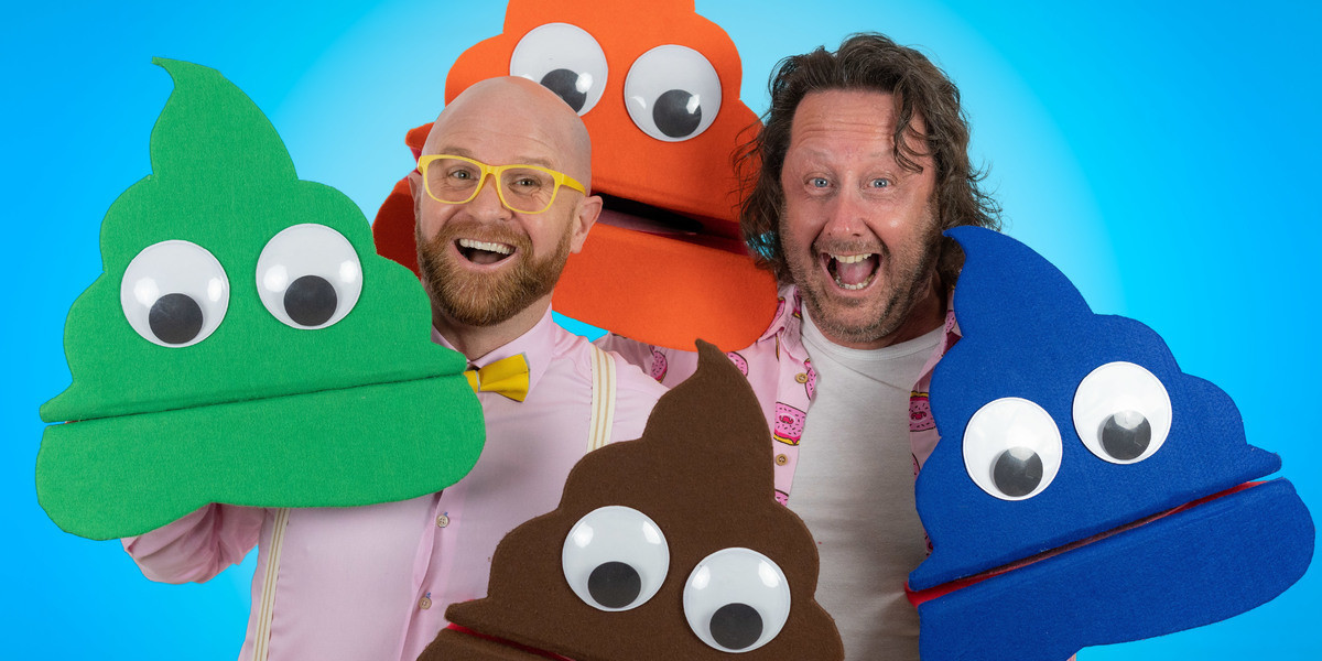Two men in pink shirts hold a collection of multi-coloured 'poop puppets' while grinning broadly.