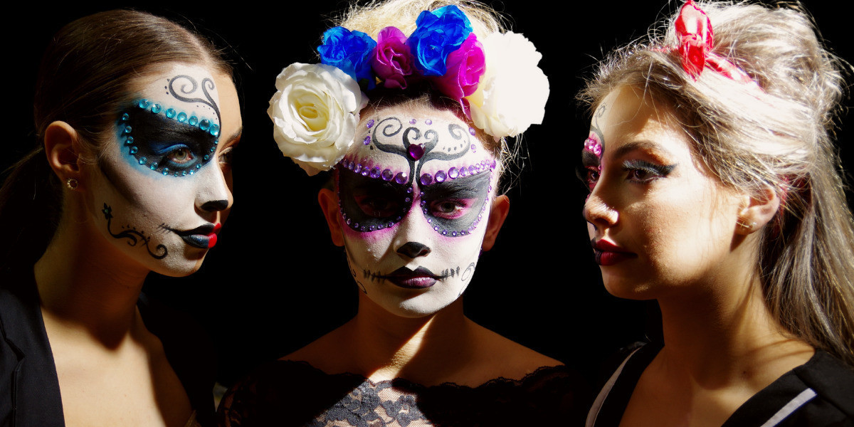 A picture of 3 girls faces with their faces painted as skulls.