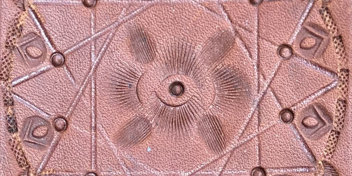 Photograph of stamped leather. The pattern is varied but in a circle.