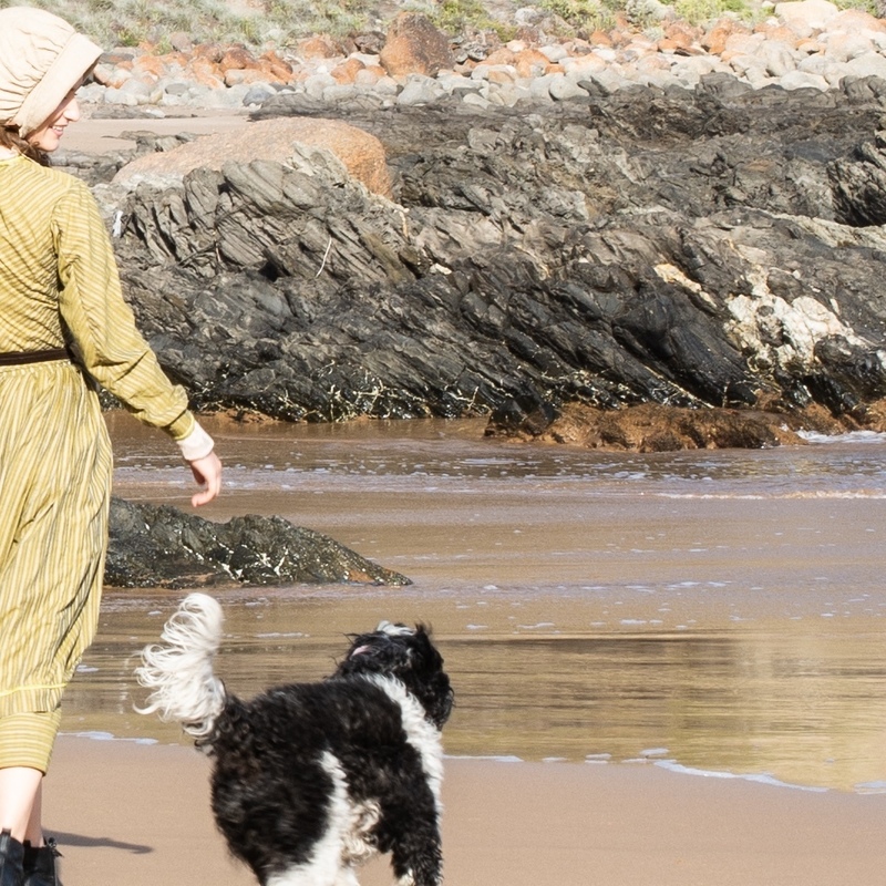 Mary Anning walking along the beach with her best friend, her dog Tray