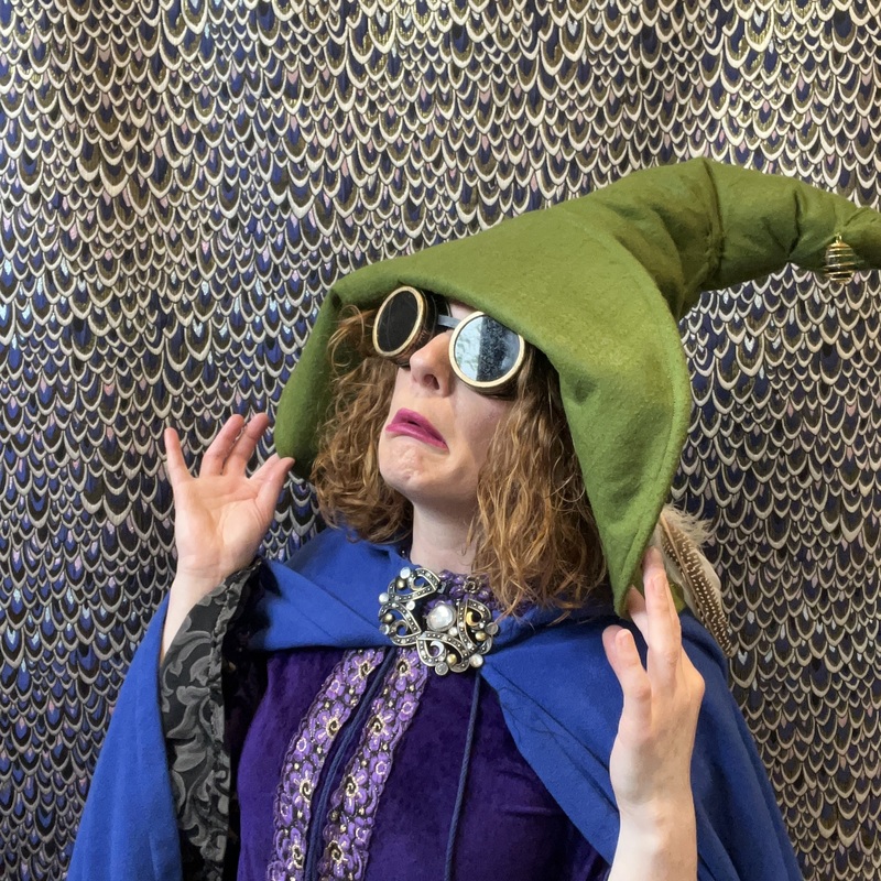 A picture of Winni Wizard holding her hat and reacting to something shocking.